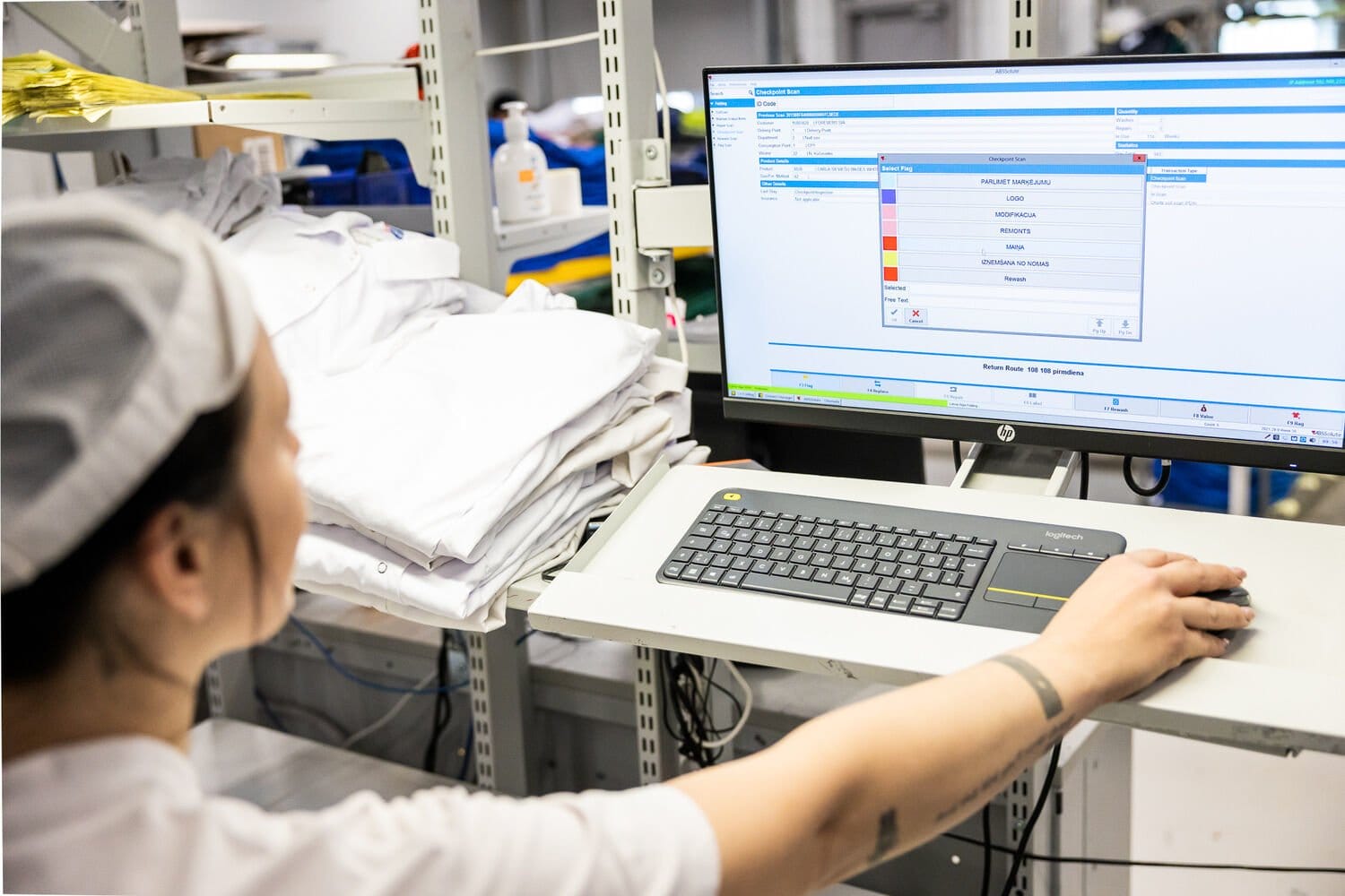 worker at computer checking clothing with RFID chip technology